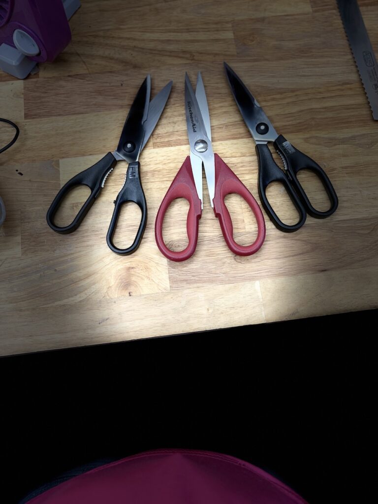 3 pairs of Scissors laying on a bench after being sharpened.